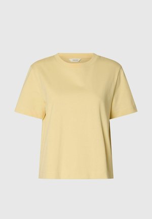 Kortermet, lys gul bomulls-t-skjorte med rund hals og rett kant på ensfarget grå bakgrunn.