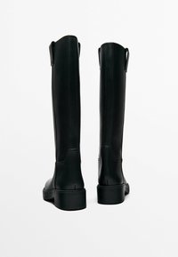 Black leather knee-high boots with a matte finish, featuring two pull tabs at the top and a thick rubber sole.