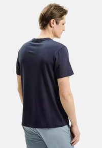 Granatowa bawełniana koszulka z krótkim rękawem, okrągłym dekoltem, prostym wzorem i luźnym krojem, pokazana z tyłu.