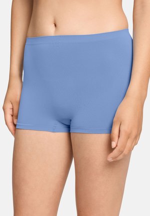 Kvinde iført lyseblå sømløse boyshorts, der viser maveområdet og øvre lår mod en ensfarvet baggrund.
