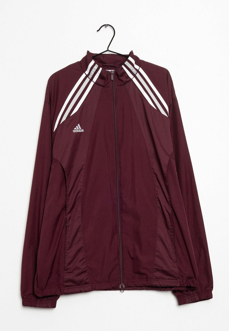 Bordeaux Adidas zip-up jack met witte strepen op de schouders, elastische mouwen en tailleband, hangend aan een zwarte hanger tegen een witte achtergrond.