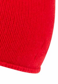 Rød strikket beanie med ribbet tekstur. Kanten har en glat finish, og stoffet viser en let nøddeagtig overflade. Letvægtig og tætsiddende pasform.
