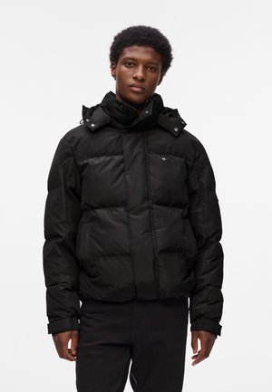 Black puffer jacket with a high collar and detachable hood, featuring a zip closure, elastic cuffs, and a small logo on the chest.