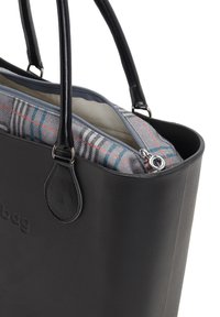 Mustahdud musta nahkakott kahe käepidemega, mille sees on osaliselt avatud plaidses mustris kott, kus on hõbedane tõmblukk.