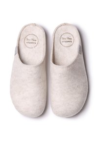 Vita filttofflor med mjuk textur, med en rund form och slip-on-design. Etiketten säger "Toni Pons tofflor" med en sydd detalj.