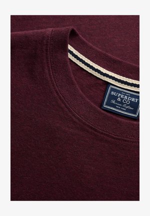 Dieprode crewneck trui met geribde kraag en wit-blauw gestreepte binnenhalsband, voorzien van een donkerblauw Superdry & Co merklabel.