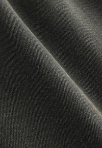 Črnen jeans tkanina z subtilno teksturo, ki prikazuje nežen padec in tkani vzorec v bližnjem pogledu.