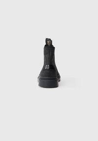 Sorte læder ankelstøvler med en kraftig sål, elastiske sidestykker og prægning på ryggen. Glat tekstur og minimalistisk design.