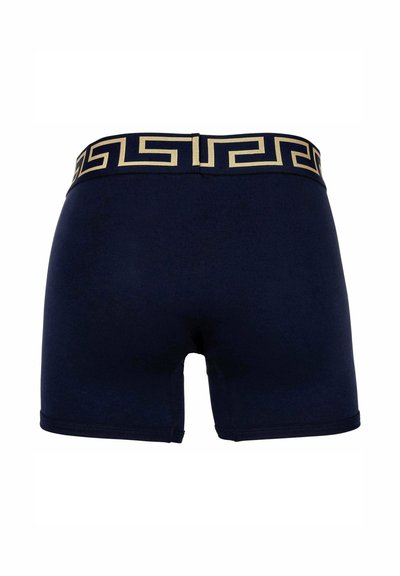 Navy blue boxer shorts featuring a gold Greek key pattern on the waistband, made from a smooth, stretchy material with a fitted design.