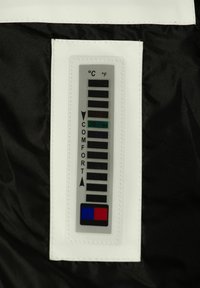 Etichetta di classificazione della temperatura su tessuto nero, con un bordo bianco. Include una scala in Celsius e Fahrenheit, contrassegnata a 30°C/86°F come zona di comfort.