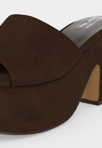 Σκούρο καφέ σουέτ mule με πλατφόρμα, παχύ μεσαίο τακούνι και ανοιχτή μύτη.