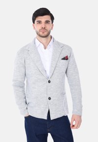 Cardigan grigio chiaro realizzato in tessuto morbido e strutturato; presenta colletto a revers, due tasche frontali e un fazzoletto da taschino nero con dettagli rossi.