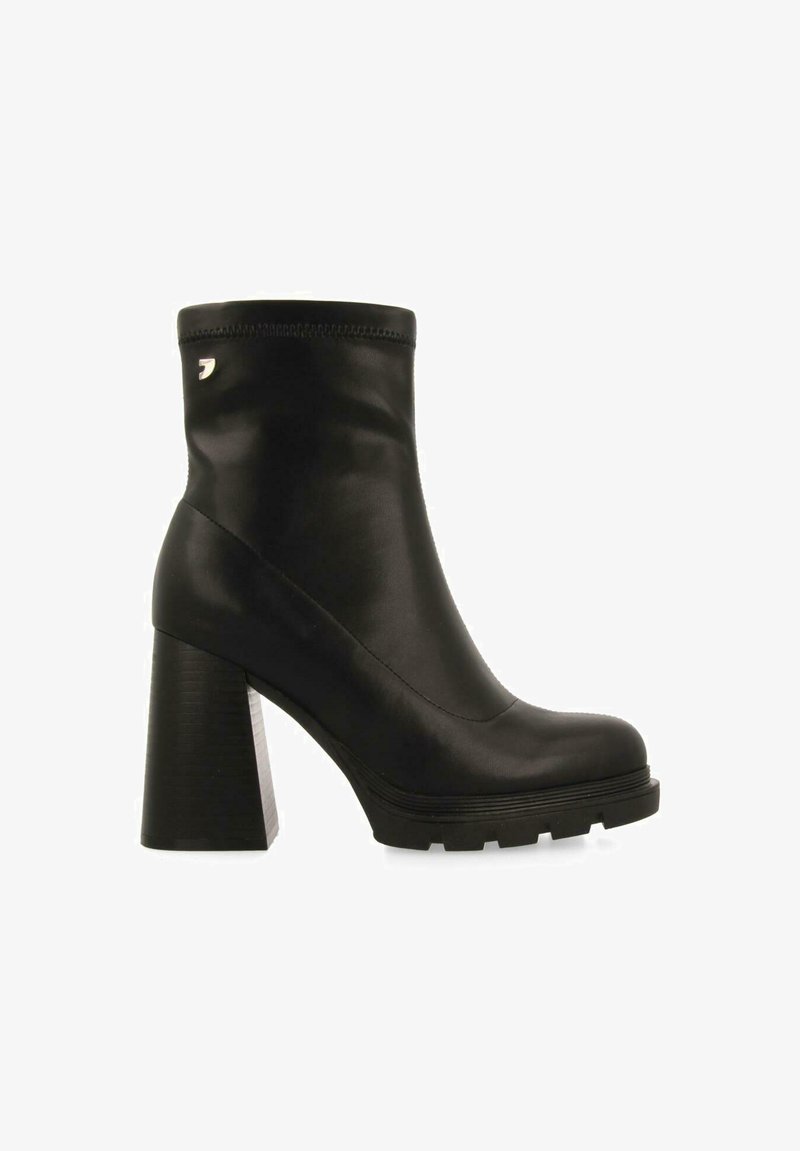 Botines negros con un tacón alto y grueso, material de cuero liso, punta redondeada y detalles de costura en el tobillo. Incluye acento de logo.