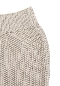 Close-up of beige knitted fabric with a ribbed edge, showing detailed knit texture and stitches.