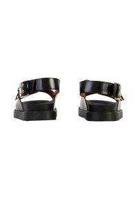 Paire de sandales en cuir noir avec des brides à la cheville et des fermetures à boucle, vues de dos sur un fond blanc.