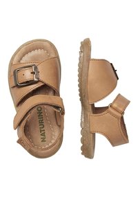 Karmelowe skórzane sandały z zapięciem na klamrę, regulowanym zapięciem na rzep oraz teksturowaną gumową podeszwą o zaokrąglonych krawędziach.