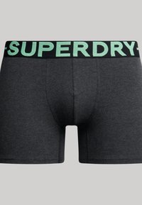 Heren boxer briefs in donkergrijs katoen met een zwarte elastische tailleband waarop mintgroene "SUPERDRY" branding staat. Soepele textuur, aansluitend ontwerp, midden boven de dijen.