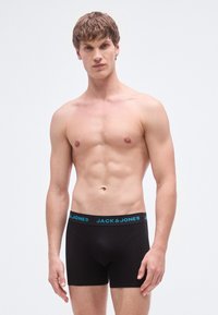 Schwarze Boxershorts mit einem türkisfarbenen Taillenbund, der das Logo "JACK & JONES" trägt. Glatter Stoff mit einer eng anliegenden Passform.