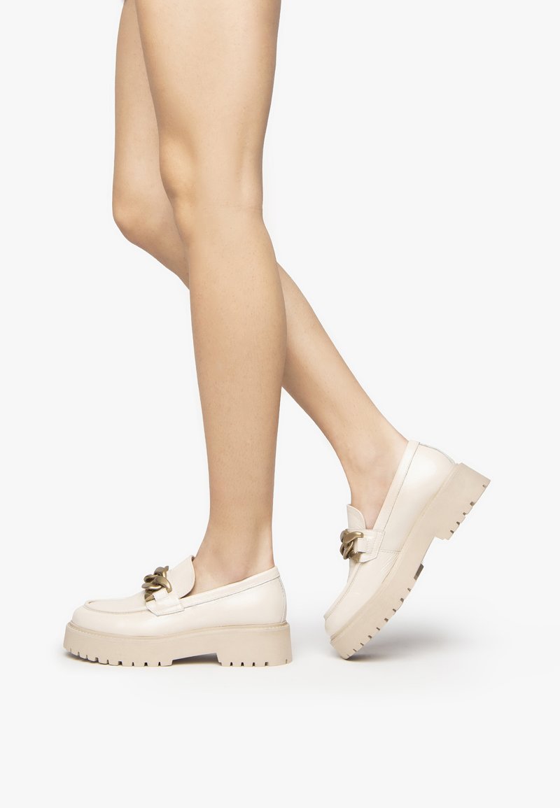 Chunky platform loafers in cream leather with a textured finish, featuring a decorative gold-tone buckle and a rugged sole design.