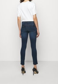 Tight jeans i mörkblå denim, med fem-fickors design och subtil sömnad. Stylar med en kortärmad vit skjorta och svarta klackar.