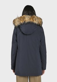 Námořnický parka s odnímatelnou umělou kožešinou na kapuci, dlouhými rukávy, elastickým pasem a bočními kapsami. Hladká tkanina s matným povrchem.