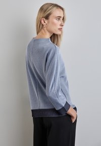 Felpa a righe blu chiaro con scollatura rotonda, maniche lunghe e polsini a costine scuri. Presenta una vestibilità comoda e una texture liscia.