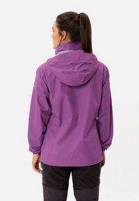 Giacca impermeabile viola con cappuccio, dotata di polsini elastici, una vestibilità leggermente comoda e una texture liscia. Dettagli grigi lungo il colletto.