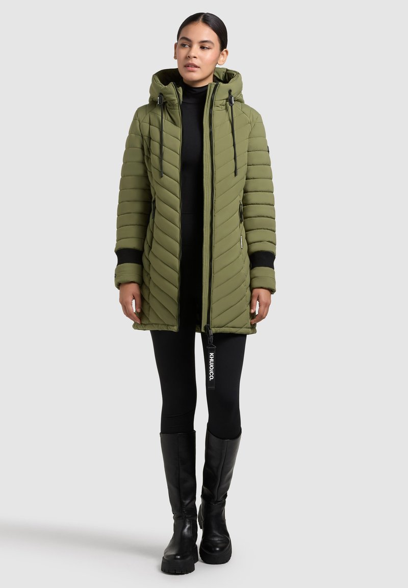 Parka imbottita verde oliva con cappuccio, chiusura con zip e trapuntatura diagonale. Presenta polsini neri e un'etichetta con logo sul cursore della zip.