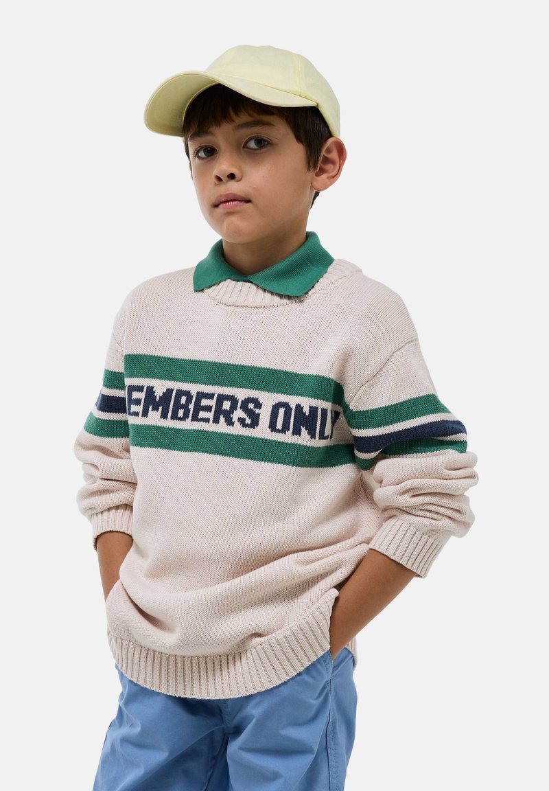 Pull en tricot beige avec des rayures vertes et bleu marine. Texte "MEMBERS ONLY" sur la poitrine. Tissu léger, col rond, poignets côtelés.