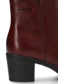 Bota de tobillo de cuero burdeos con un acabado suave, tacón cuadrado negro, detalles de costura sutiles y diseño de punta redondeada.