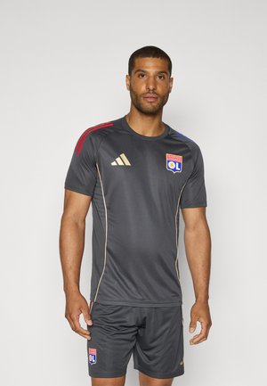Maillot de sport gris foncé avec des accents dorés, comportant des manches courtes, des bandes latérales rouges et bleues, et un logo d'équipe brodé sur la poitrine.