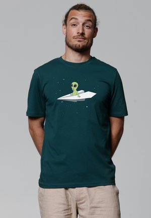 Dunkelblaues Kurzarm-T-Shirt mit einem grafischen Motiv eines grünen Aliens, das auf einem weißen Papierflieger vor einem sternenklaren Hintergrund sitzt.