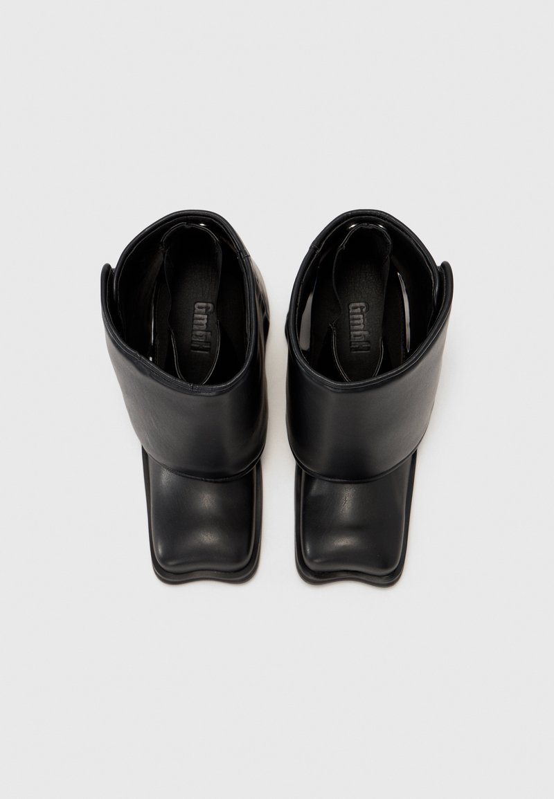 Zwarte enkellaarsjes met een glad leren afwerking, vierkante neus en een omgevouwen manchetontwerp. Binnenvoering zichtbaar bij de opening.