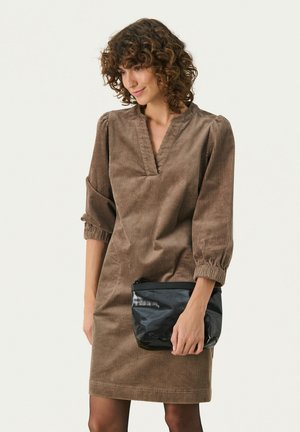 Abito in corduroy marrone con maniche a tre quarti e scollo a V, abbinato a una borsa a tracolla nera. Tessuto liscio, design al ginocchio.