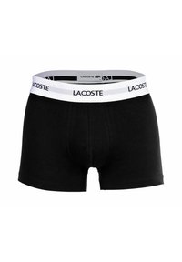 Czarne bokserki wykonane z miękkiego materiału. Posiadają białą elastyczną talię z logo "LACOSTE". Płaskie szwy i modelująca kieszonka.