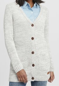 Ljusgrå cardigan gjord av kraftig stickad material. Har V-ringning, träknappar, två framfickor och ribbade manschetter.