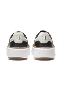 Schwarze Ledersneaker mit weißen Akzenten, die ein strukturiertes Design, eine dicke weiße Sohle und ein eingeprägtes Logo auf der Rückseite aufweisen, mit einer Sohle aus Gummi.