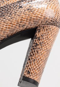 Escarpin à talon haut à semelle noire, motif peau de serpent marron et noir, montré en vue latérale rapprochée.