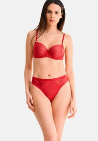 Ensemble de lingerie rouge comprenant un soutien-gorge balconnet avec des panneaux transparent et des bretelles ajustables, associé à une culotte taille haute avec des détails de conception similaires.