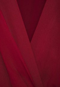 Burgundy fabric with a soft, textured finish. The material features layered folds with a smooth drape, creating a deep V shape.