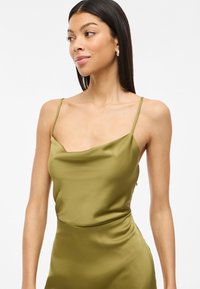 Olive green satin camisole with a draped neckline, thin straps, and smooth texture, fitted through the torso. Simple and elegant design.