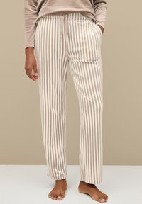 Pantalones de pijama a rayas beige y crema con cintura elástica, bolsillos laterales y un corte relajado, fabricados con material suave.