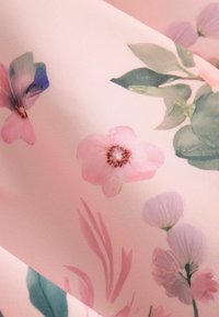Puha rózsaszín anyag finoman nyomtatott virágokkal rózsaszín, lila árnyalatokban és zöld levelekkel, lágy virágmintát alkotva.