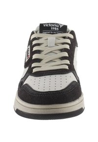 Sneaker con una toma superiore in suede nero, dettagli in pelle bianca, punta perforata e lacci beige. Presenta un logo sulla linguetta e una suola testurizzata.