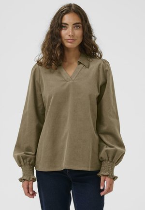 Olive green corduroy blouse with a V-neck, puffed sleeves, and smocked cuffs. The fabric has a soft texture and a relaxed fit.