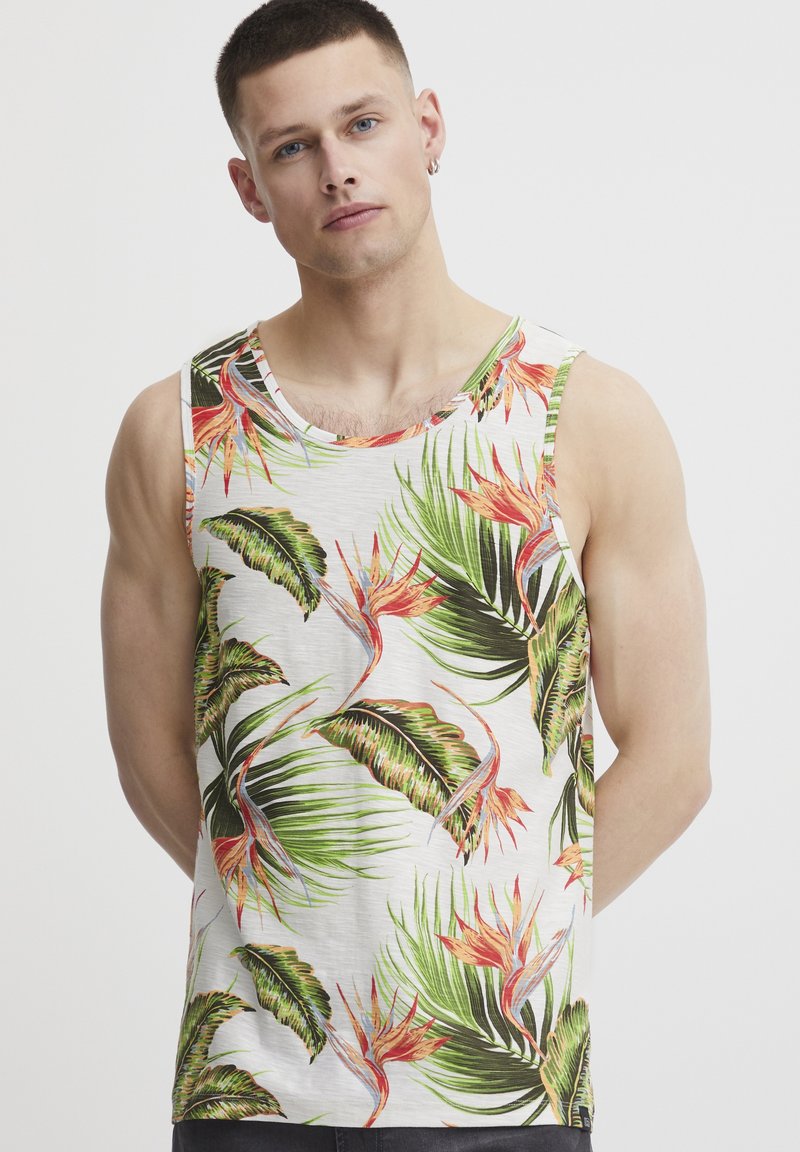 Tropical print tank top featuring a white background with green palm leaves and vibrant orange flowers. Made of lightweight fabric.