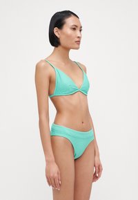 Set de bikini verde mentă, compus dintr-un top triunghiular cu textură în relief și bretele ajustabile, asortat cu un fund înalt cu textură în relief.