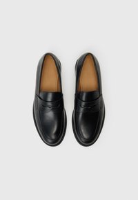 Black leather loafers with a smooth finish, round toe, and stitched detailing along the sole. Interior features a brown leather lining.