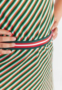 Striped dress featuring green, orange, and white lines, with a solid green waistband accented by a red and white stripe.
