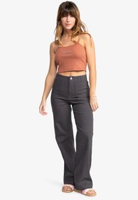 Gray high-waisted pants with a straight leg, two front pockets, and a button closure, paired with a rust-colored cropped tank top.